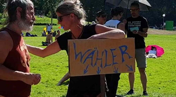 Frau lehnt ihren Ellenbogen auf ihr Plakat mit Aufschrift und 4 Pfeilen, die nach unten zeigen.
