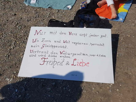 Zwei Füße auf einem Handtuch: Zu Füßen ein weißes Schild mit Aufschrift.