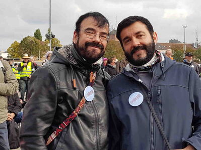 Zwei lächelnde fesche Männer mit Bart und je den gleichen weißen Button