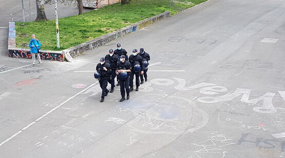 Sechs Polizisten mit Masken marschieren in 2erReihe