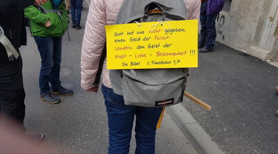 Frau mit gelbem Schild über dem Rucksack