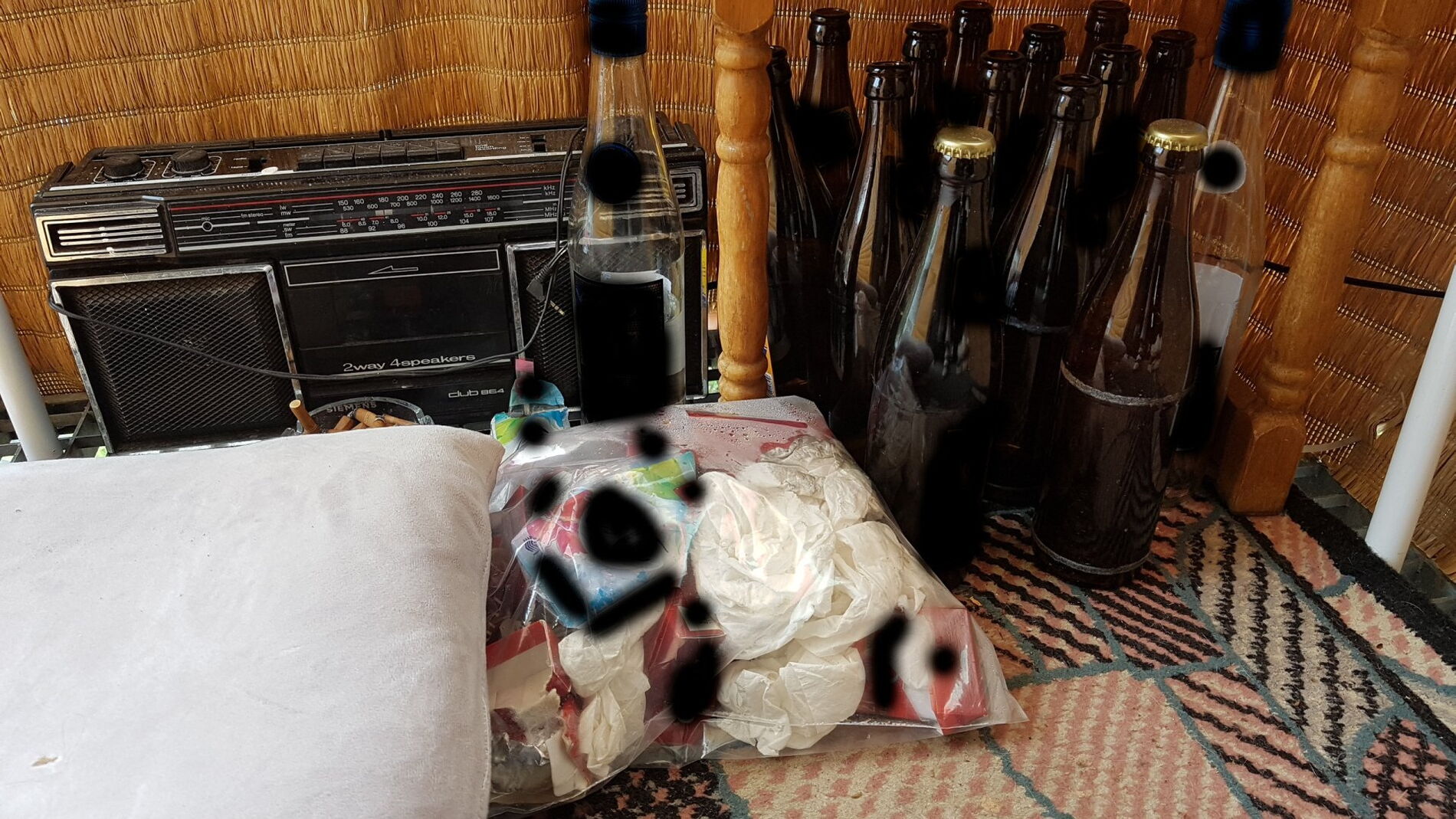 Ein altes Radio, elf leere Flaschen bir und zwei Volle, 2 leere Schnapsflaschen, eine Plastiktüte mit Rotzfahnen und ein voller Aschenbecher auf der Terrase